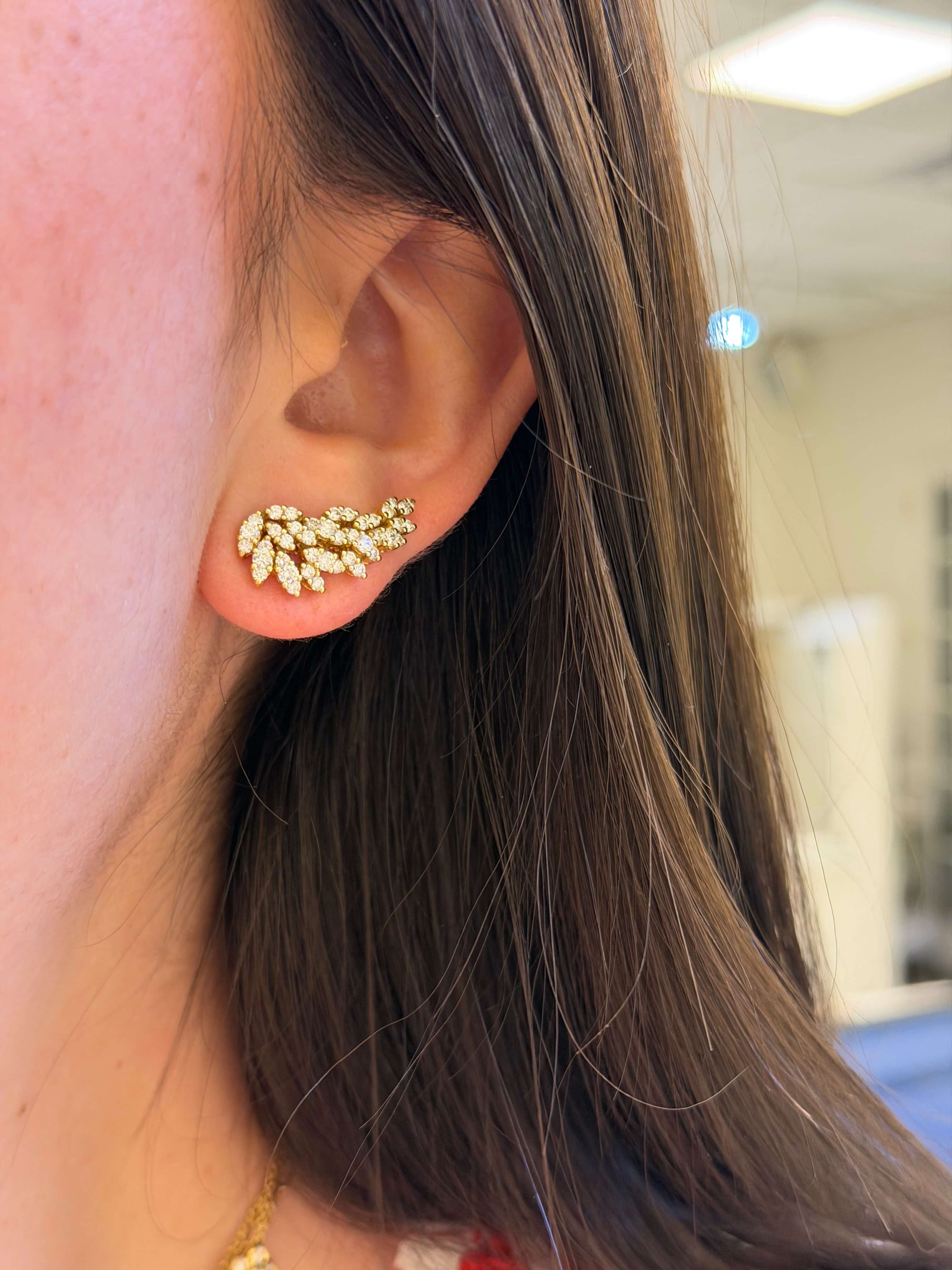 Close-up of an ear wearing a gold earring with small stones.