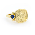 An 18kt yellow gold ring featuring a central dog engraving with small sapphires set on the side.