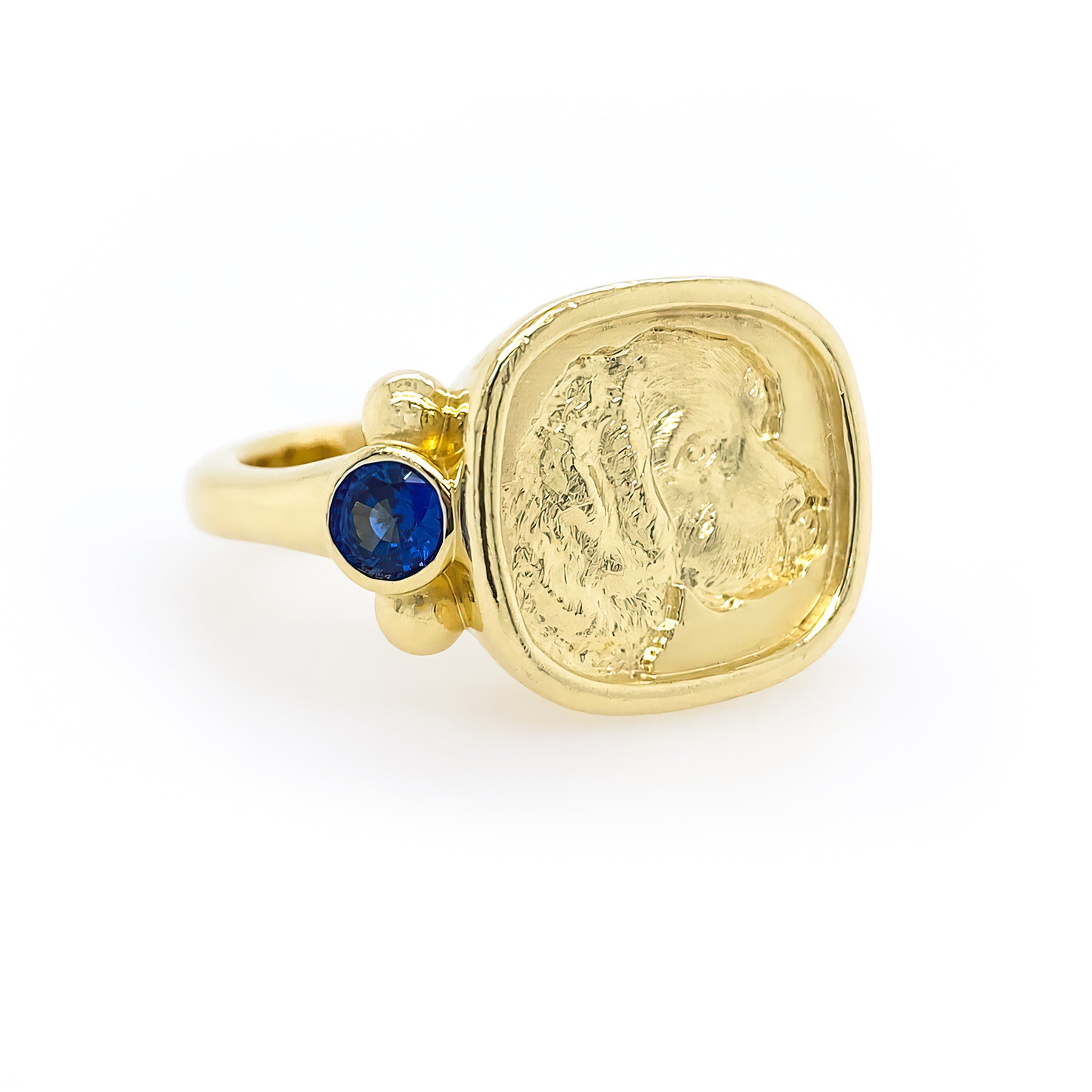 An 18kt yellow gold ring featuring a central dog engraving with small sapphires set on the side.