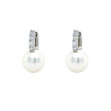 A pair of 18K white gold pearl and diamond earrings with the pearls hanging down.