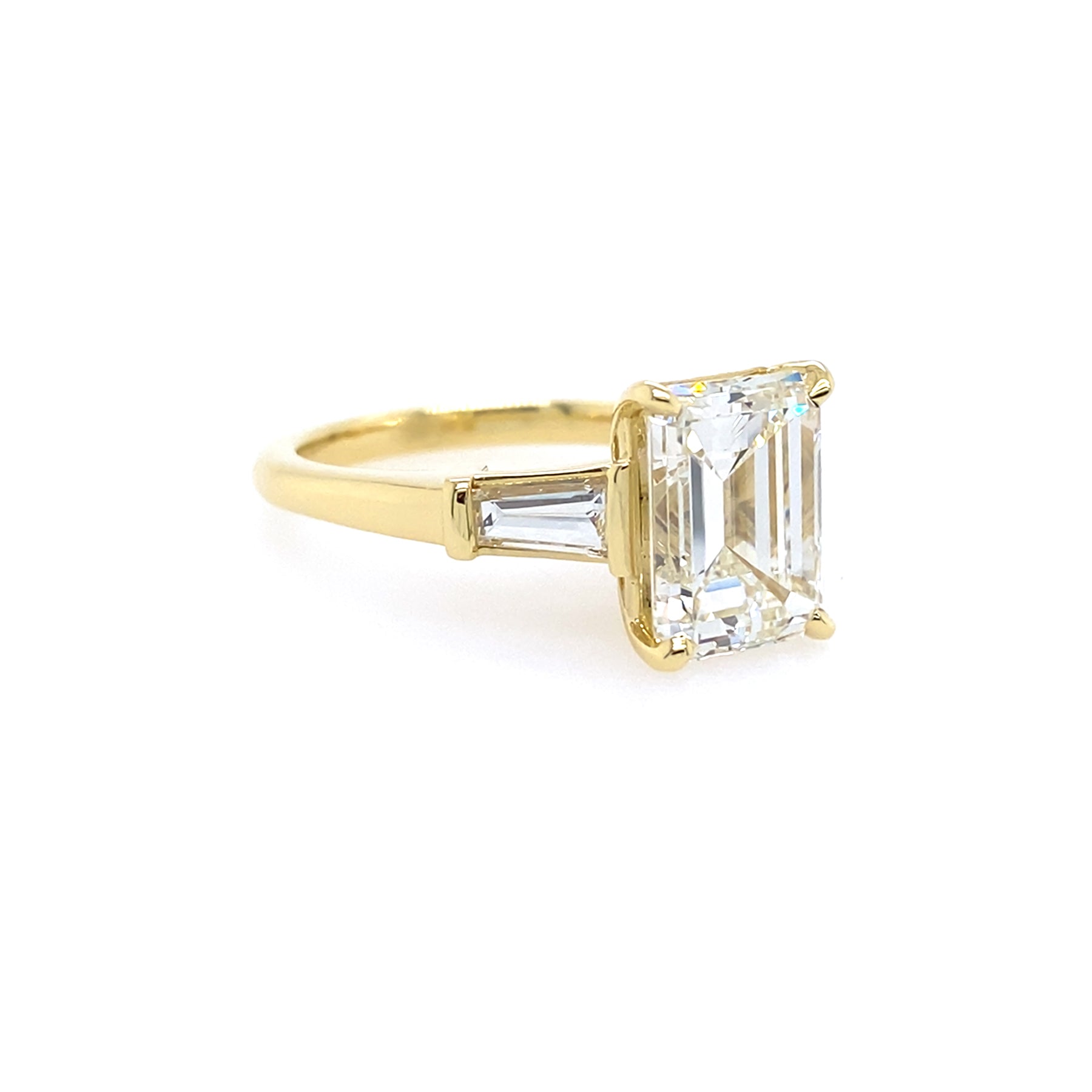 Gold ring with a large emerald cut diamond with taped baguettes 