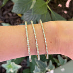 Three slim 14K yellow gold diamond bracelets on a woman's wrist
