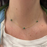 18K Gold necklace with green emerald gemstones worn by a woman