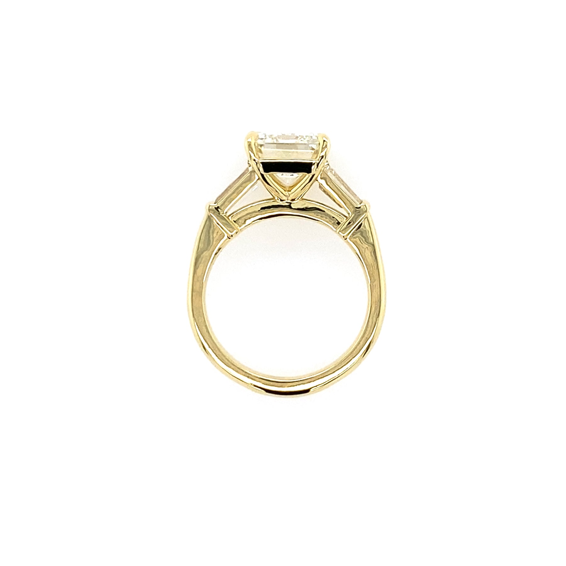 Side View Gold ring with a large emerald cut diamond with taped baguettes 