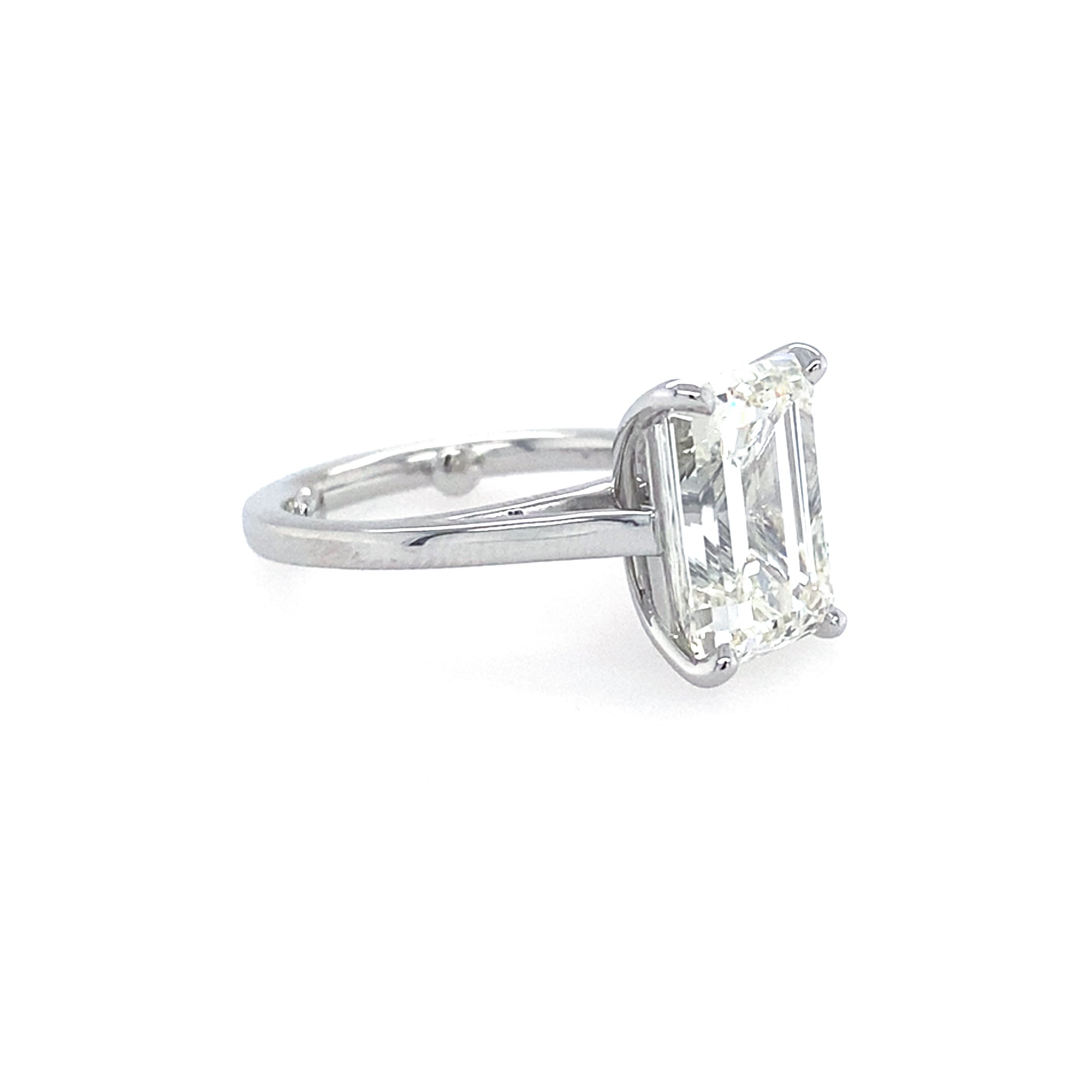 Diamond ring with emerald cut diamond on a white background
