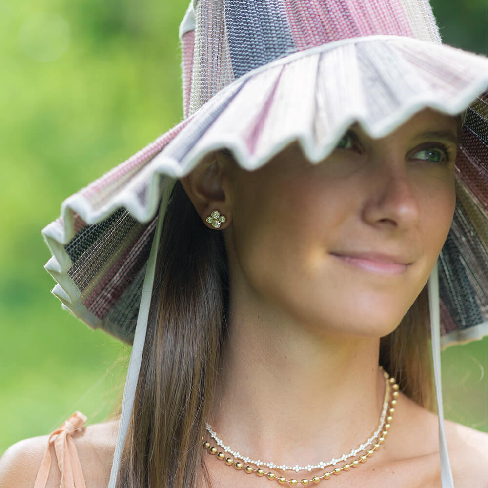 Woman wearing a colorful sun hat and Anderson gold and diamond stud earrings