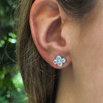 Close-up of a woman wearing a platinum diamond earring with a blurred green background