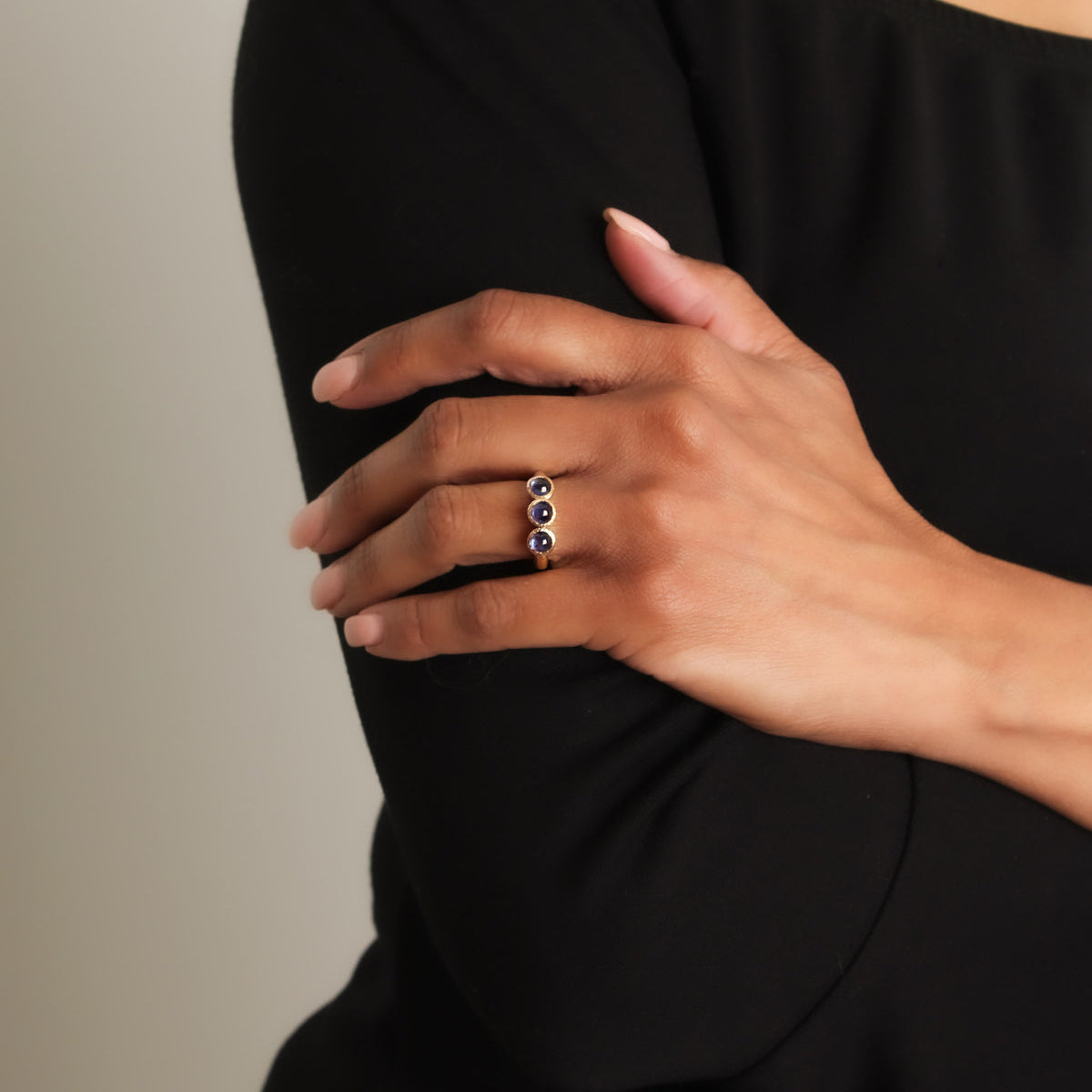 Woman wearing a blue sapphire ring with a black background