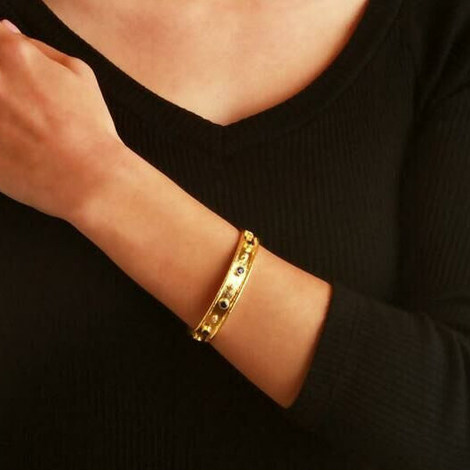 19K Gold bracelet on a woman's wrist with a black background