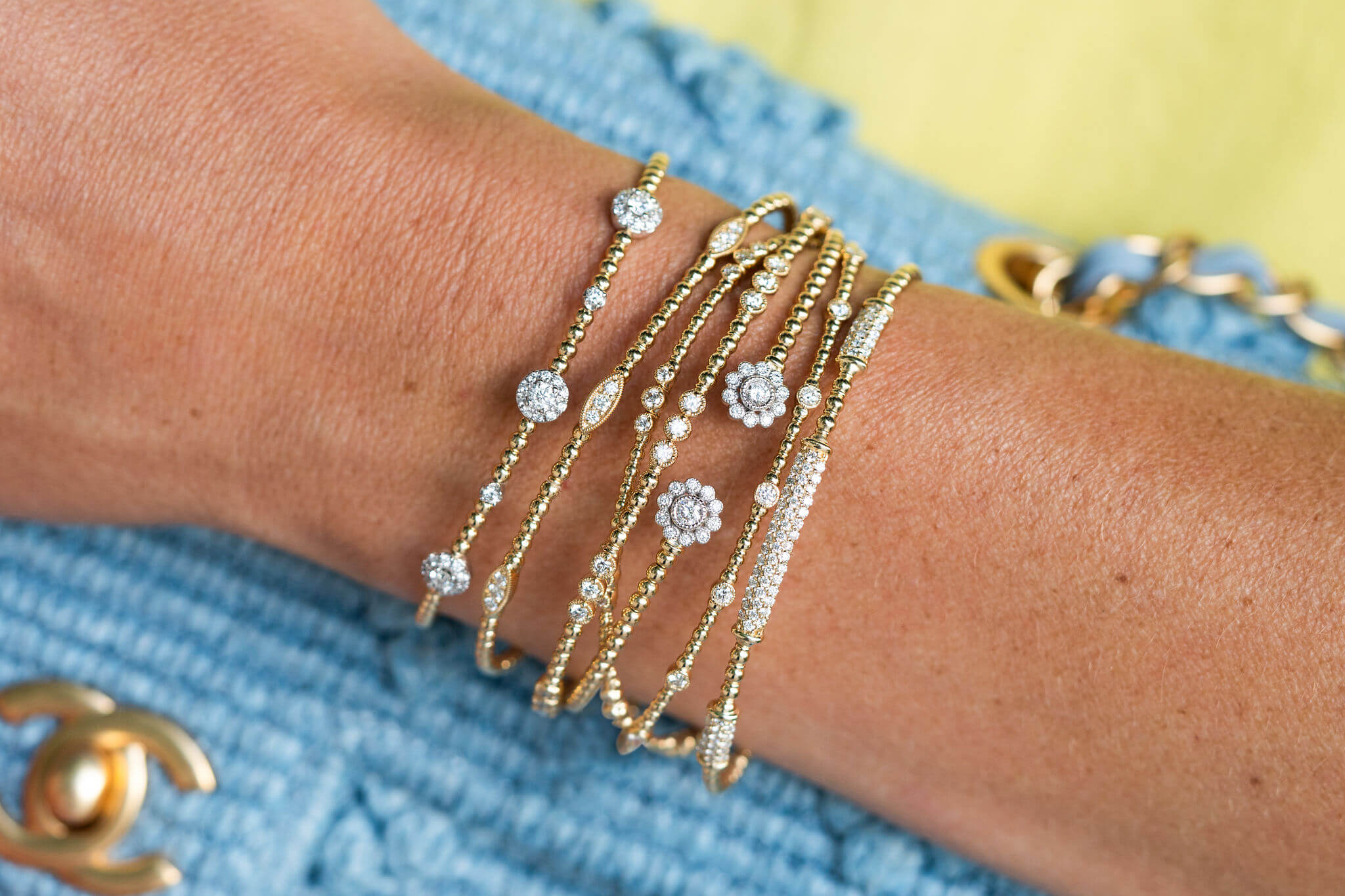 woman's wrist with a collection of fine jewelry bracelets offered at Laura Pearce Ltd.