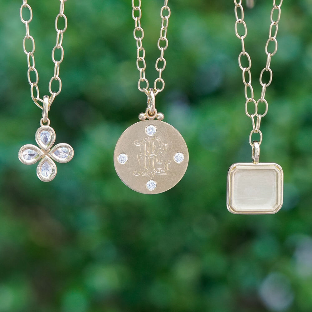 Three silver necklaces with pendants on a blurred green background