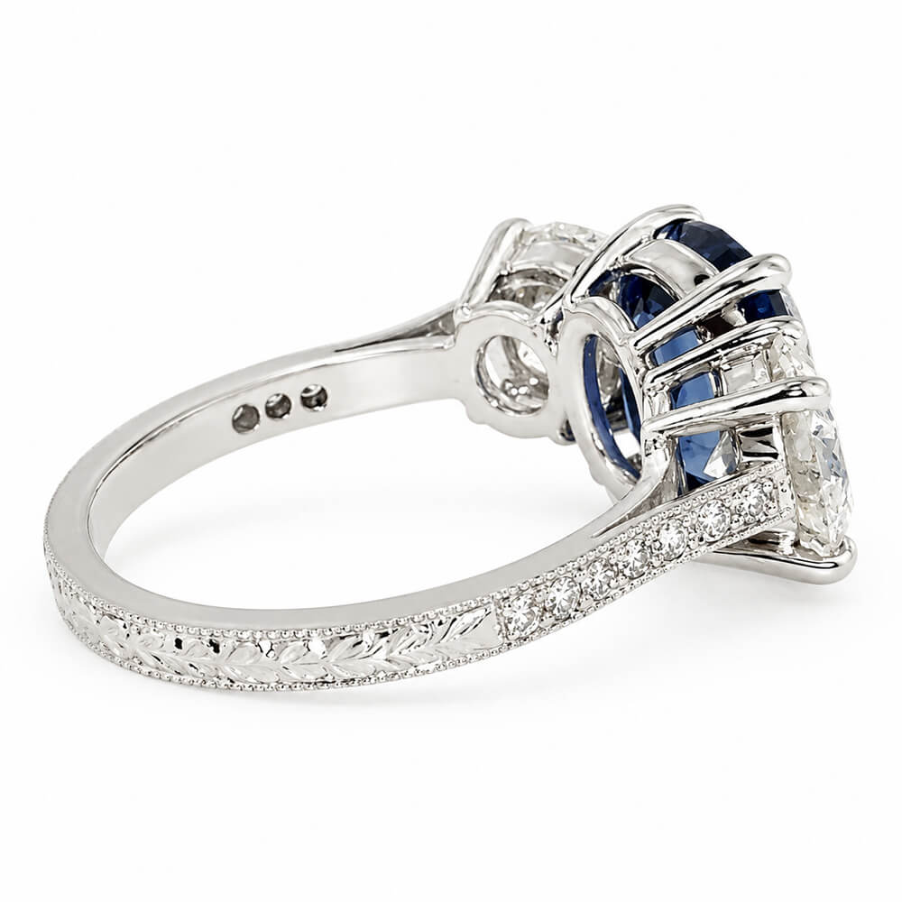 A platinum ring featuring a deep blue sapphire and clear diamonds,  set on a diamond and filigree band against a white background.