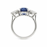 A platinum ring featuring a central rectangular blue sapphire gemstone flanked by two smaller round diamonds, shown on a plain white background.