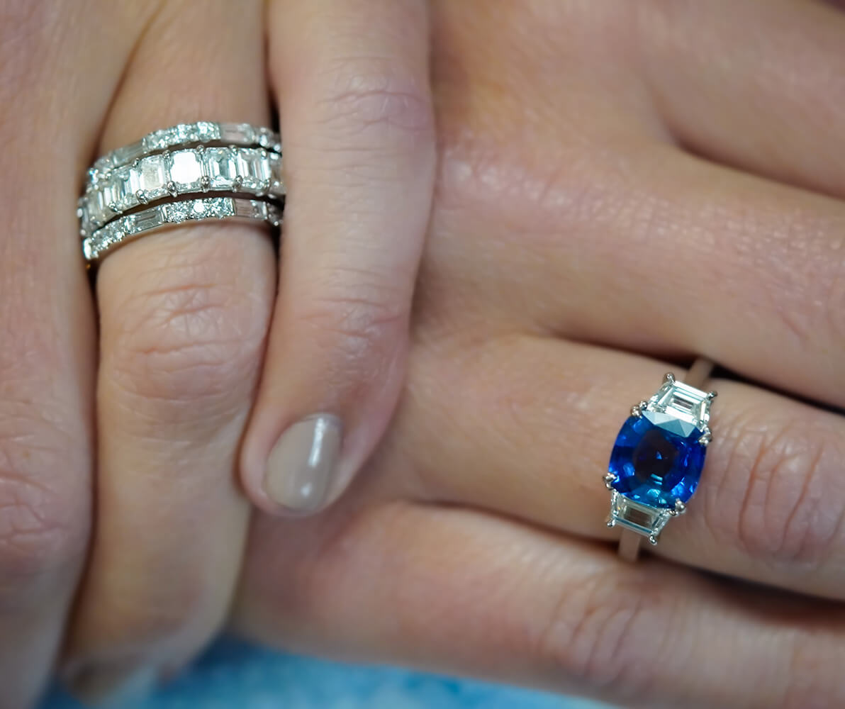 Custom designed ring featuring a cushion cut sapphire and trapezoid side diamonds in a platinum setting