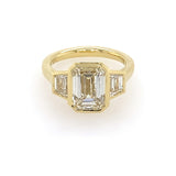 18k yellow gold bezel set emerald cut engagement ring with trapezoid side stones 