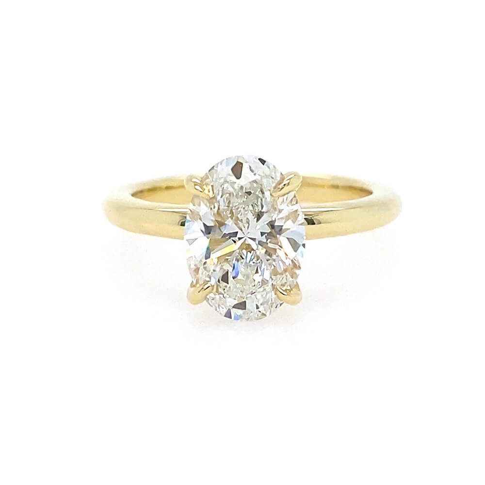 An 18K yellow gold ring featuring a large oval-cut diamond in a four-prong setting, shown against a plain white background.