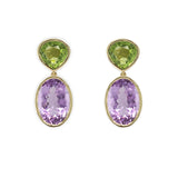 A pair of 18K yellow gold earrings featuring a large oval amethyst stone suspended from a smaller round peridot stone, set against a white background.