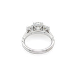 A platinum diamond ring with a three-stone setting, featuring a central round diamond and two smaller side diamonds, shown on a plain white background.