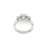 A platinum diamond ring with a three-stone setting, featuring a central round diamond and two smaller side diamonds, shown on a plain white background.