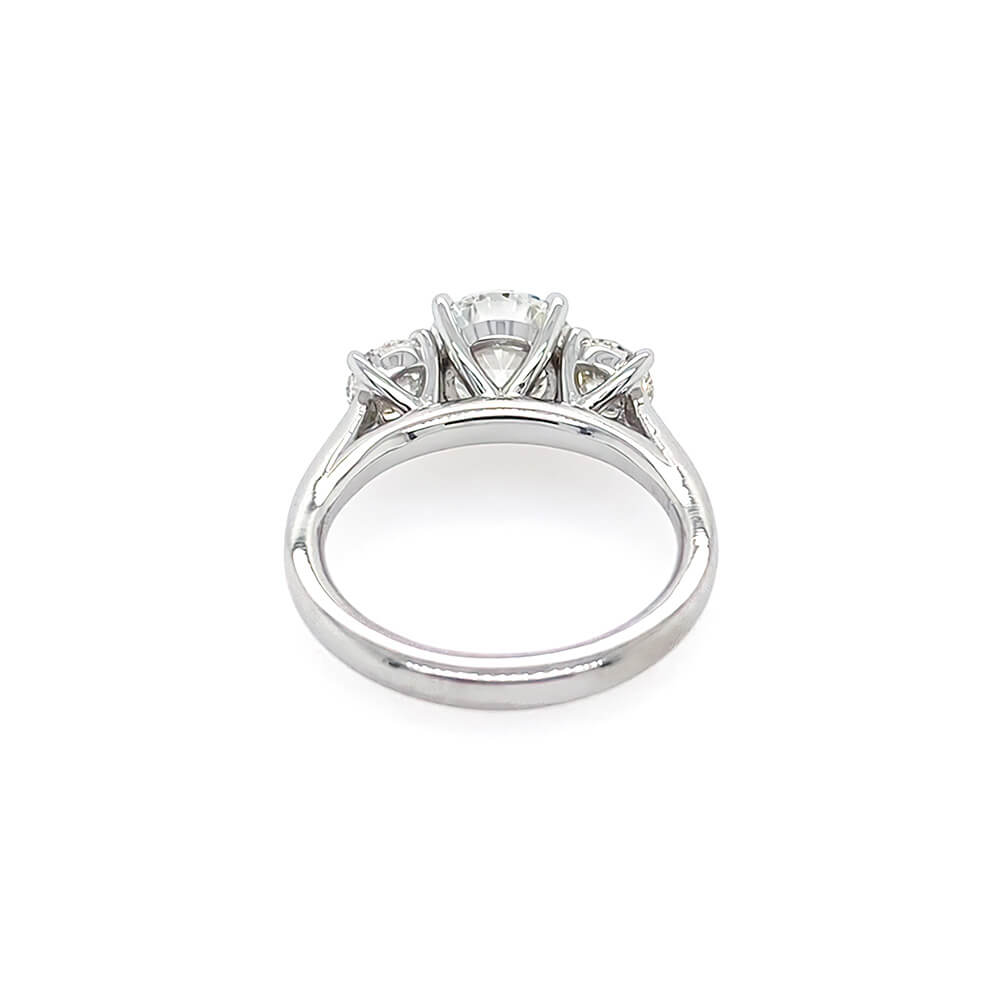 A platinum diamond ring with a three-stone setting, featuring a central round diamond and two smaller side diamonds, shown on a plain white background.