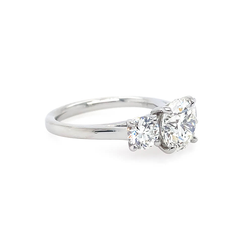 Round brilliant cut three stone diamond engagement ring in platinum - side view