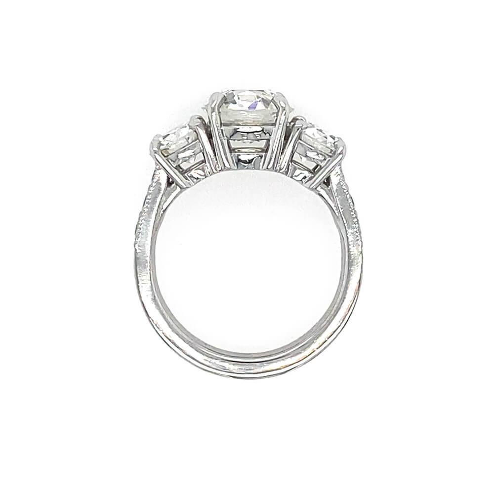 A platinum diamond ring featuring a central round diamond flanked by two round diamonds on a clean white background.