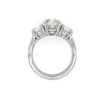 A platinum diamond ring featuring a central round diamond flanked by two round diamonds on a clean white background.