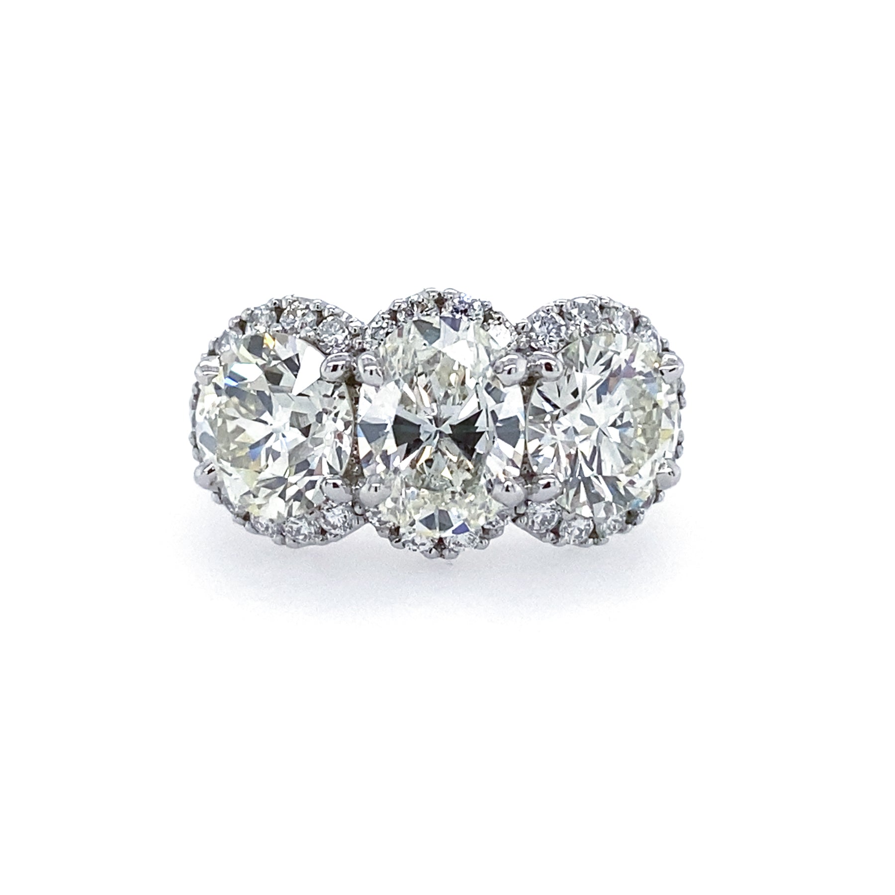 A platinum band ring with three diamond halo settings.