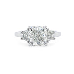 A three-stone diamond ring featuring a central cushion-cut diamond flanked by two smaller half moon diamonds on a polished platinum band, set against a plain white background.