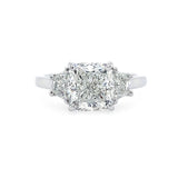 A three-stone diamond ring featuring a central cushion-cut diamond flanked by two smaller half moon diamonds on a polished platinum band, set against a plain white background.