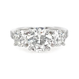 A three-stone diamond ring featuring a round center diamond flanked by two round side diamonds on a polished platinum band, set against a plain white background.