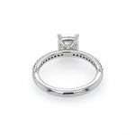 A platinum diamond ring shown from the underside, featuring a cushion-cut center stone in a four-prong setting and a pavé band with small accent diamonds, photographed on a white background.