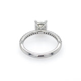 A platinum diamond ring shown from the underside, featuring a cushion-cut center stone in a four-prong setting and a pavé band with small accent diamonds, photographed on a white background.