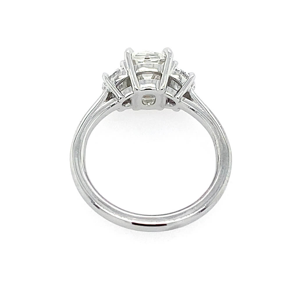 A platinum diamond ring with an old mine cut center diamond and smaller half moon side stones, shown from the back on a plain white background.