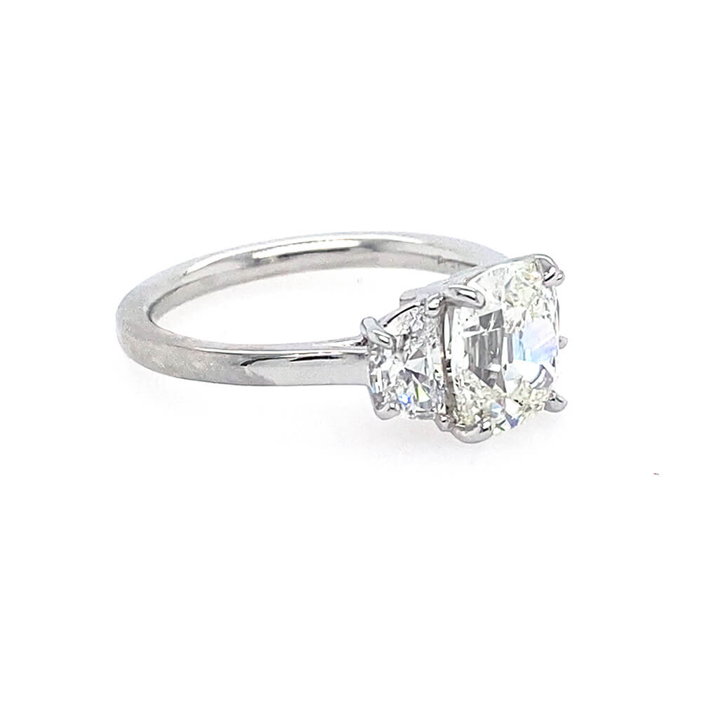 A platinum diamond ring featuring a large old-mine-cut center stone and two smaller half-moon side stones, set on a plain white background.