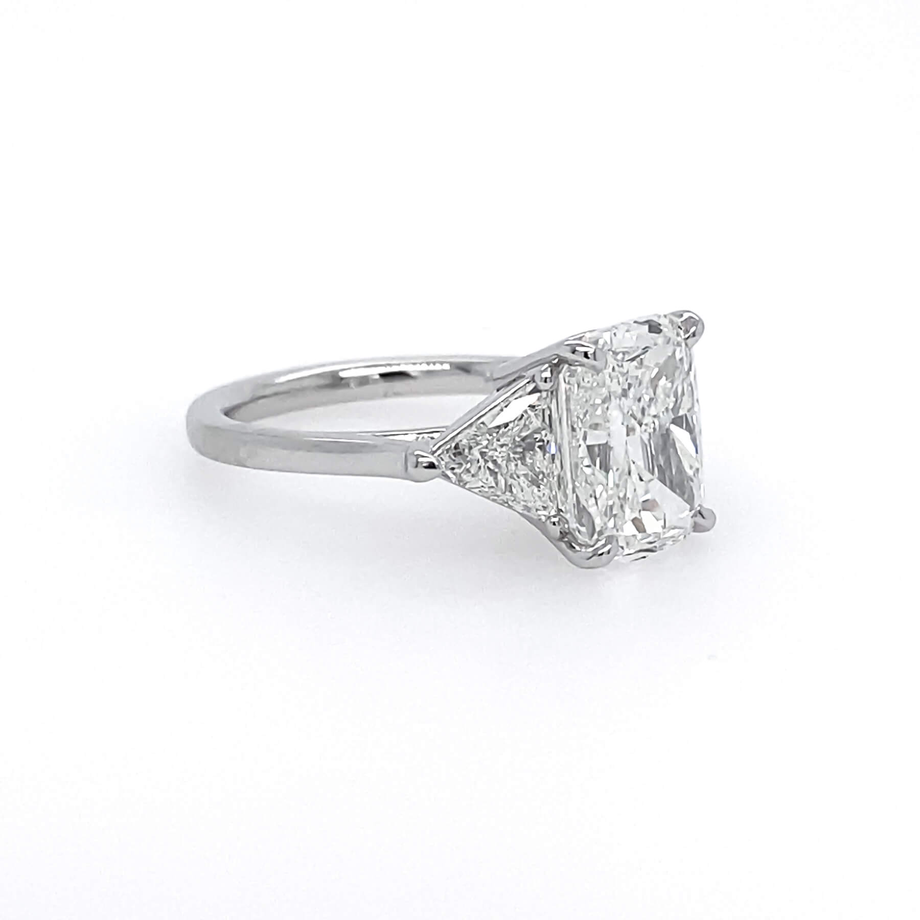 A classic diamond engagement ring featuring a rectangular cushion-cut center stone in a platinum setting on a plain white background.