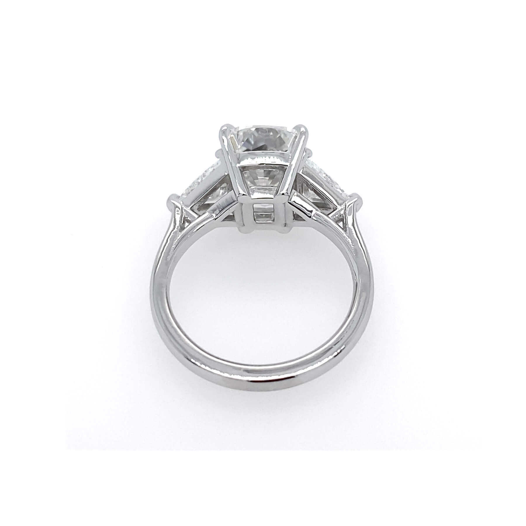 A platinum diamond ring with a large cushion cut center diamond and trillion side stones, shown from a top-down view on a white background.