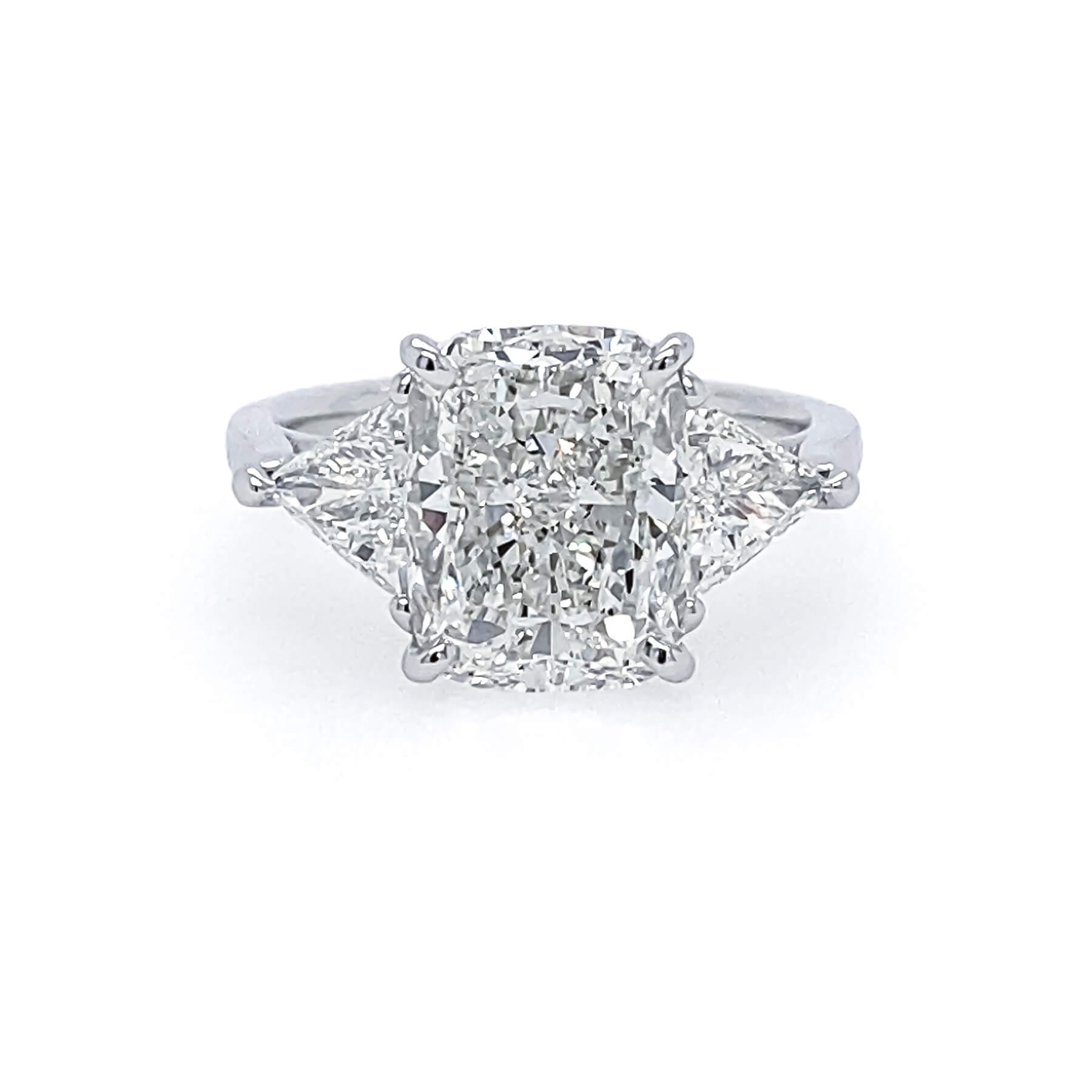 A three-stone diamond ring featuring a large rectangular cushion-cut center stone with two trillion side diamonds, set in a polished platinum band on a white background.