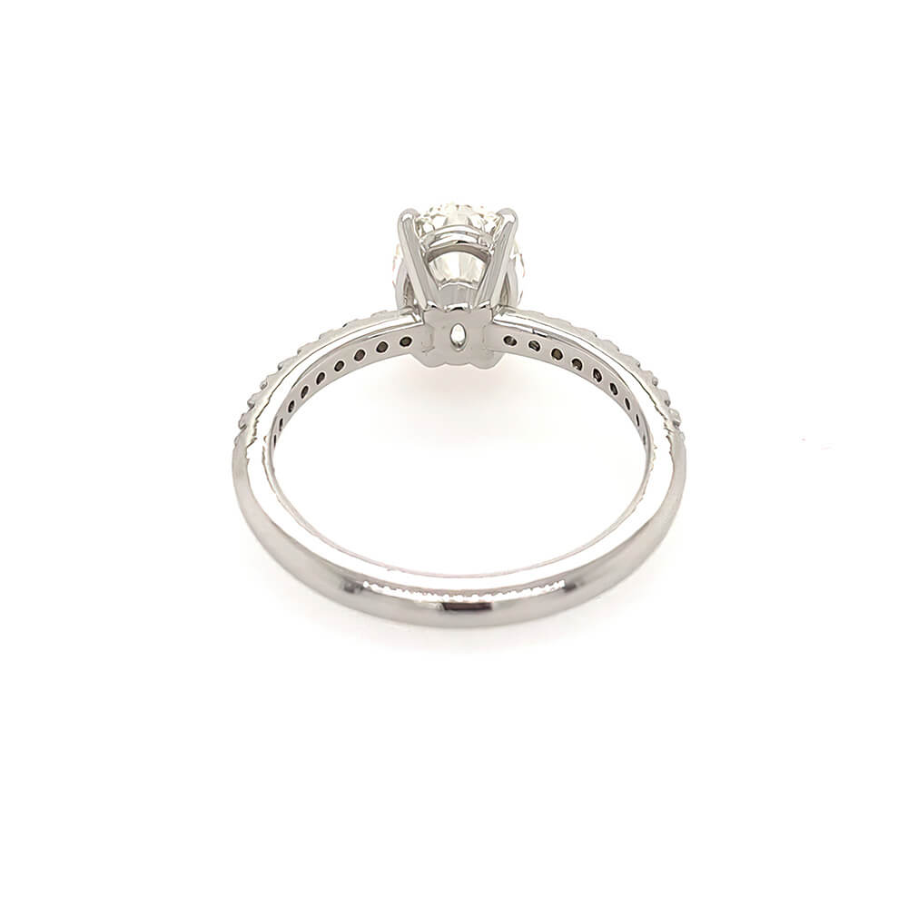 A platinum diamond ring shown from the side, featuring an oval-cut diamond in a four-prong setting with a diamond-accented band, photographed on a solid white background.
