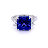A platinum ring featuring a large tanzanite gemstone surrounded by smaller trapezoid-shaped diamonds.