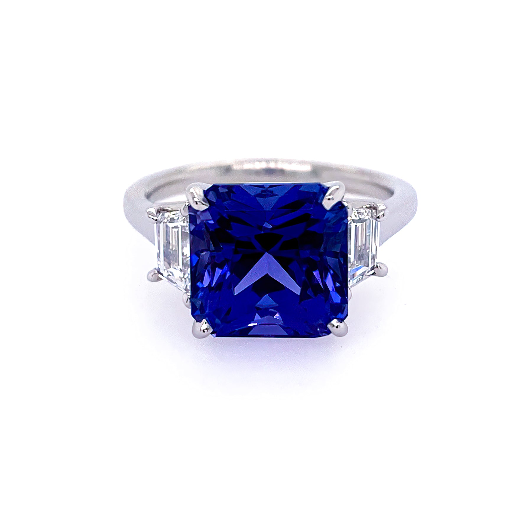 A platinum ring featuring a large tanzanite gemstone surrounded by smaller trapezoid-shaped diamonds.