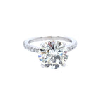 A classic solitaire engagement ring featuring a round brilliant-cut diamond set in a platinum metal band with a prong-set diamonds around the band