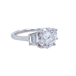 A custom-designed platinum round diamond ring with a trapezoid side stone, displayed against a white background.