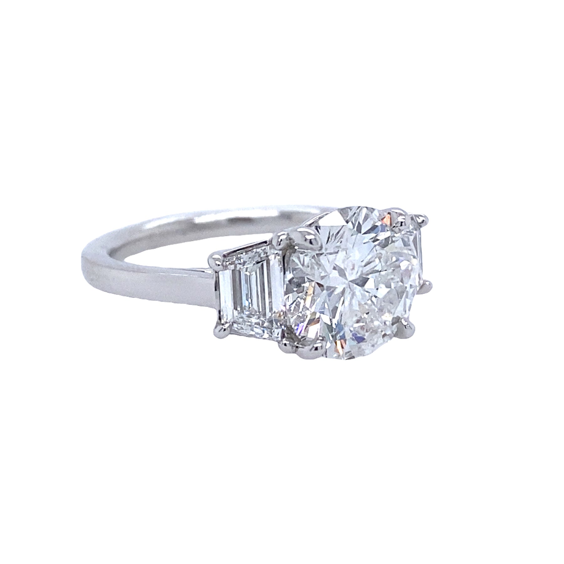 A custom-designed platinum round diamond ring with a trapezoid side stone, displayed against a white background.