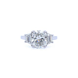 A custom-designed platinum cushion cut diamond ring with trapezoid side stones set in a platinum band