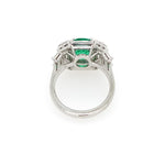 back view of platinum ring with a green emerald and diamonds
