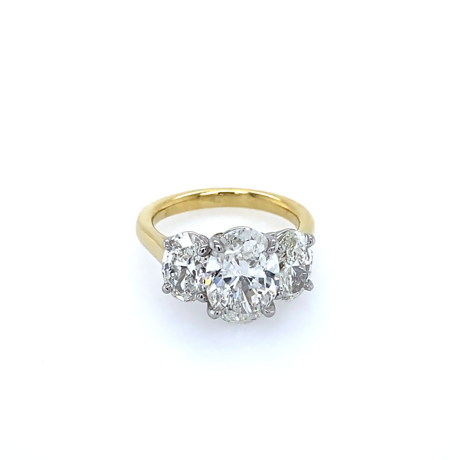 An 18K yellow gold three stone oval diamond ring with platinum prongs.