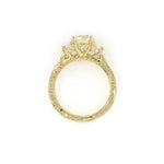 A custom designed round brilliant diamond ring with trapezoid side diamonds in hammered 18K yellow gold
