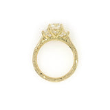 A custom designed round brilliant diamond ring with trapezoid side diamonds in hammered 18K yellow gold