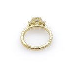 A custom designed round brilliant diamond ring with trapezoid side diamonds in hammered 18K yellow gold